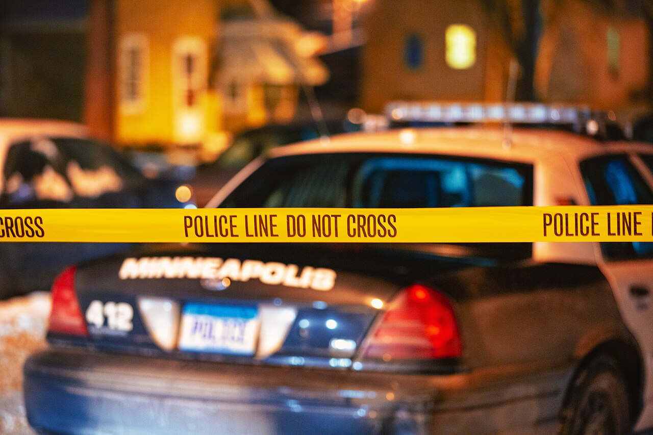 Police line tape in front of a patrol car at night