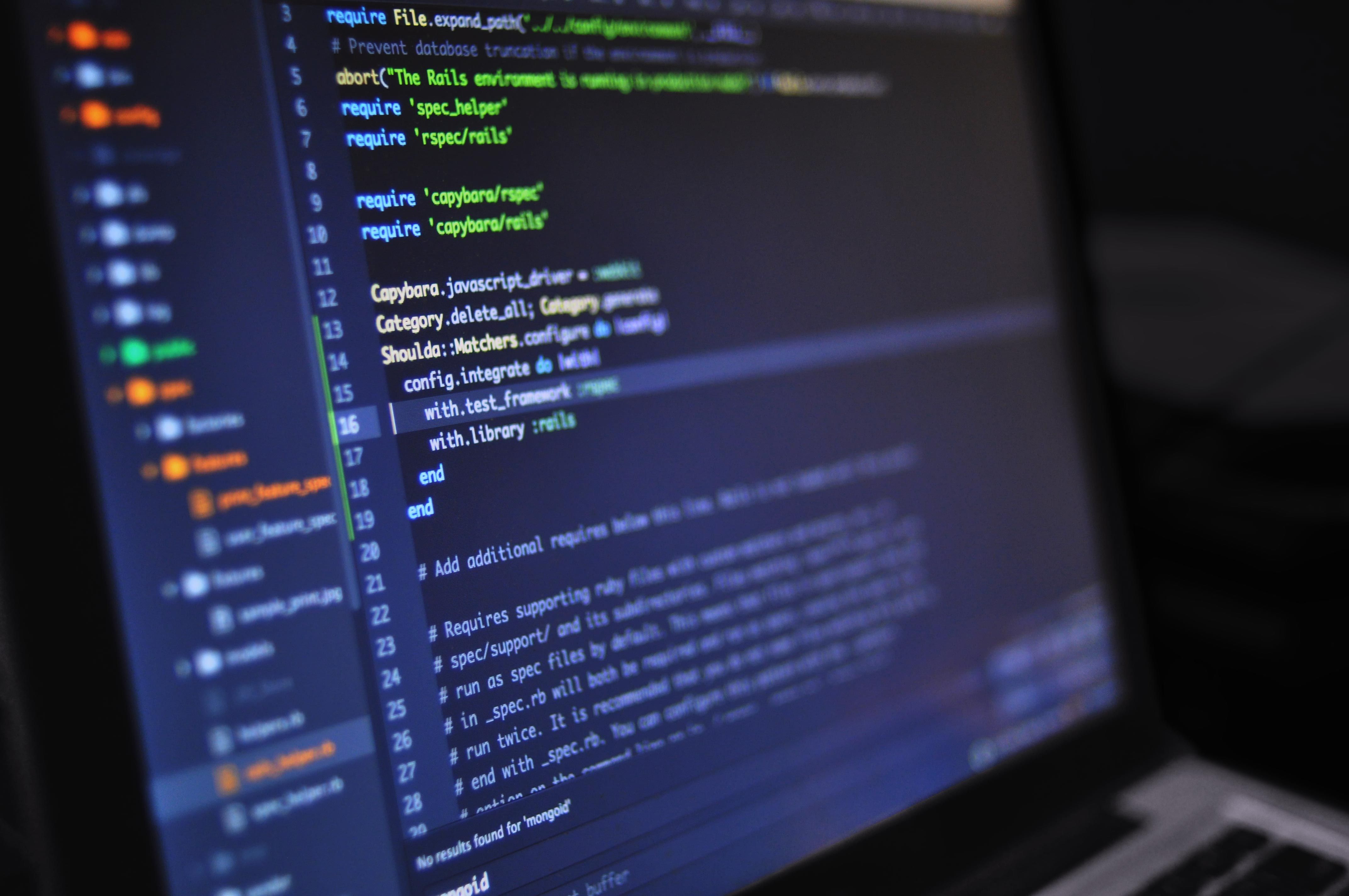 Software developer reviewing source code on multiple displays