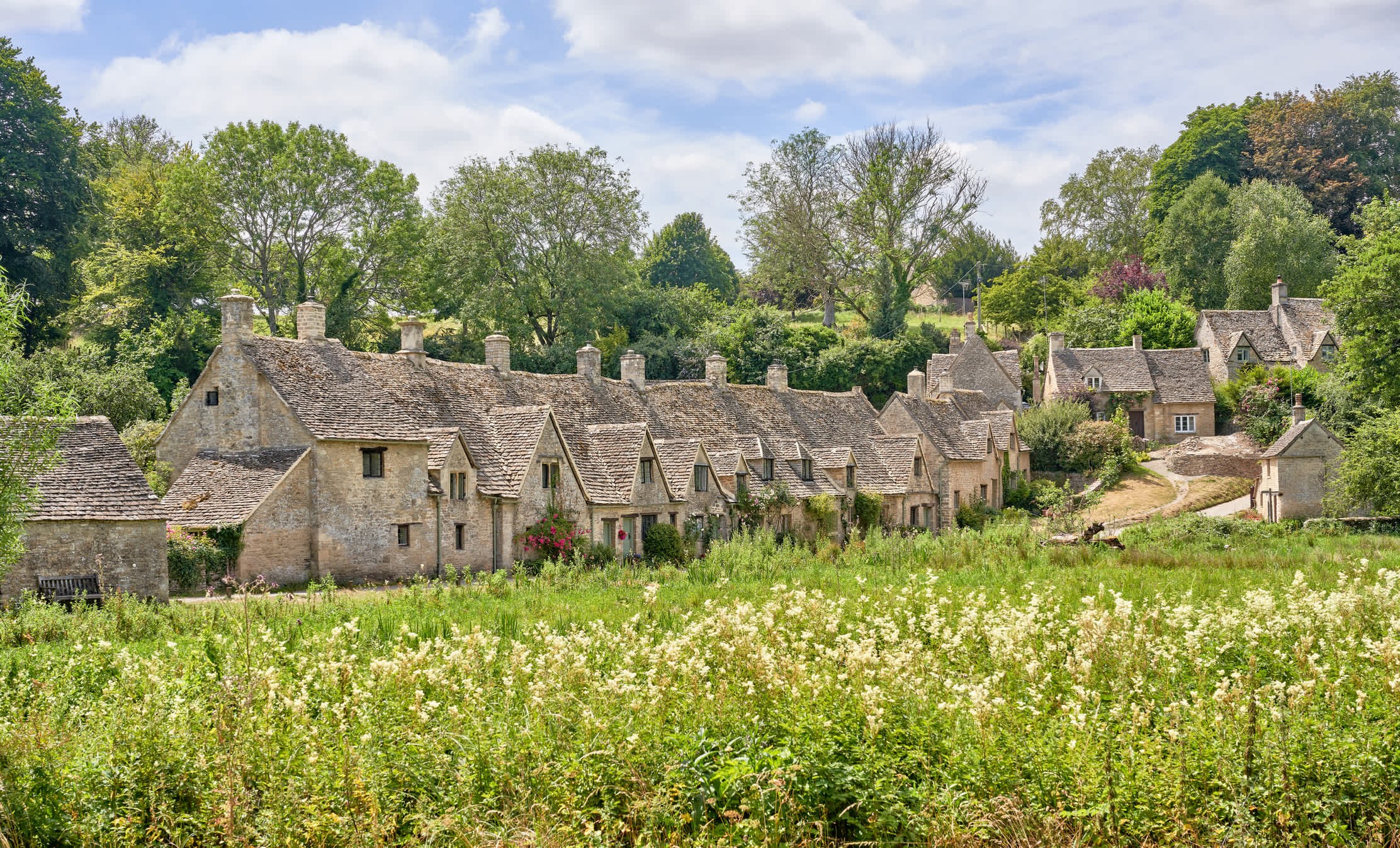 Stone cottages and a flowered meadow in the Cotswolds