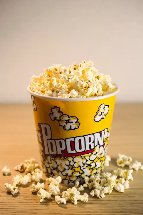 A carton of popcorn on a cinema-themed background