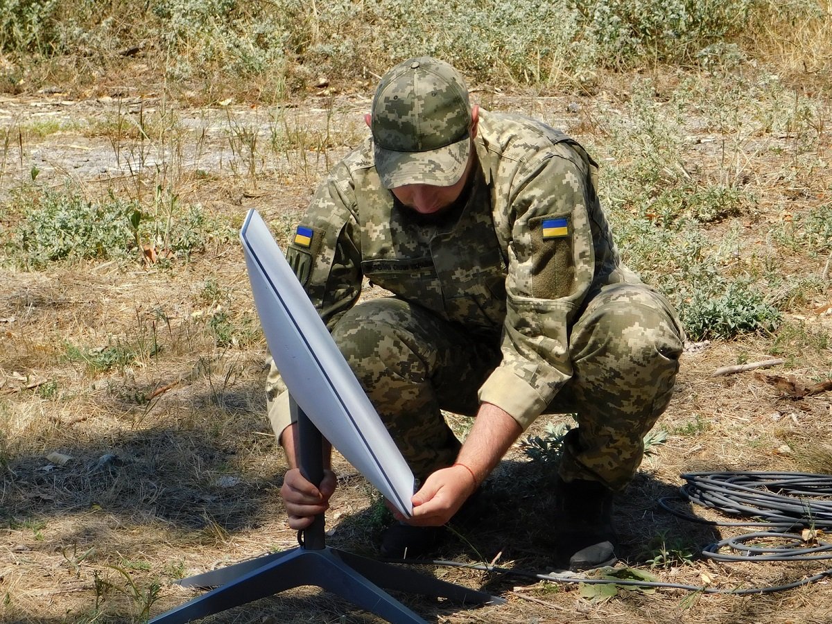 A Ukrainian serviceman setting up a Starlink terminal in the field in Ukraine