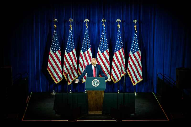 President Donald Trump at a podium — the Trump $500 checks are mailing while the $5,000 dividend awaits Congress