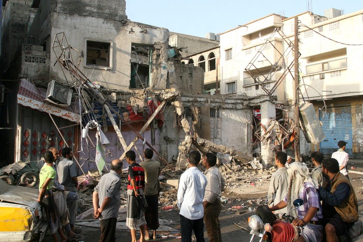 Residents beside war-damaged buildings in Taiz during the Houthi siege of Taiz