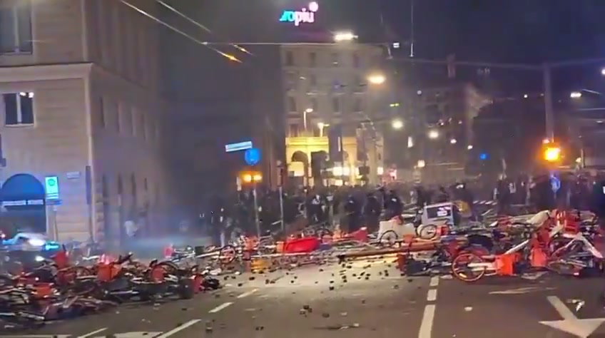 Bologna protest clashes — a barricade of overturned red rental bikes across a Bologna street at night
