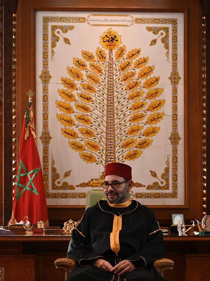 King Mohammed VI of Morocco seated beside the Moroccan flag as the country votes in the 2026 legislative elections