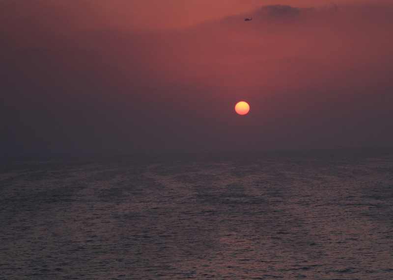 The aircraft carrier USS Carl Vinson transits the Strait of Hormuz at sunset — the waterway where six tankers were struck in a week in the October 2026 Hormuz tanker attack wave