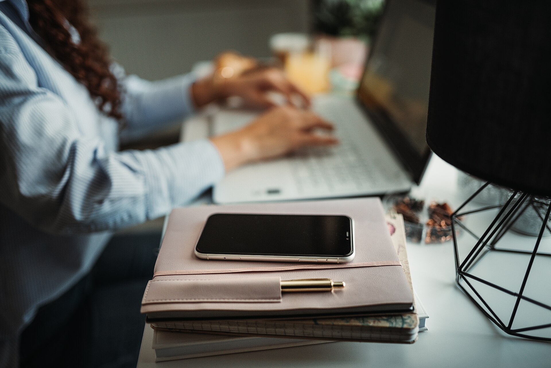 A professional working at a laptop with a planner and smartphone — the overloaded desk Claude Duet AI agent is built to manage