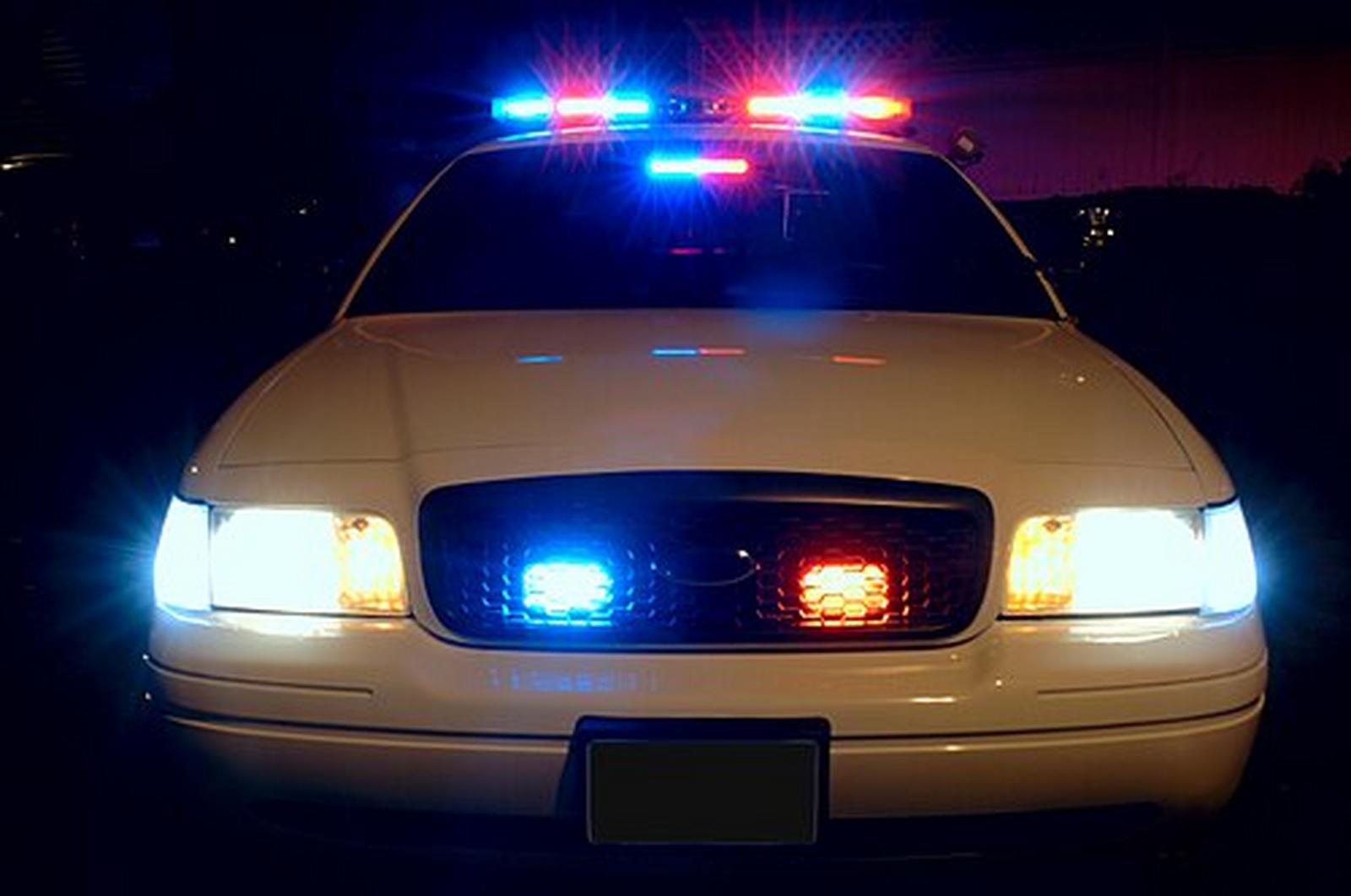 Generic police cruiser with red and blue emergency lights illuminated at night