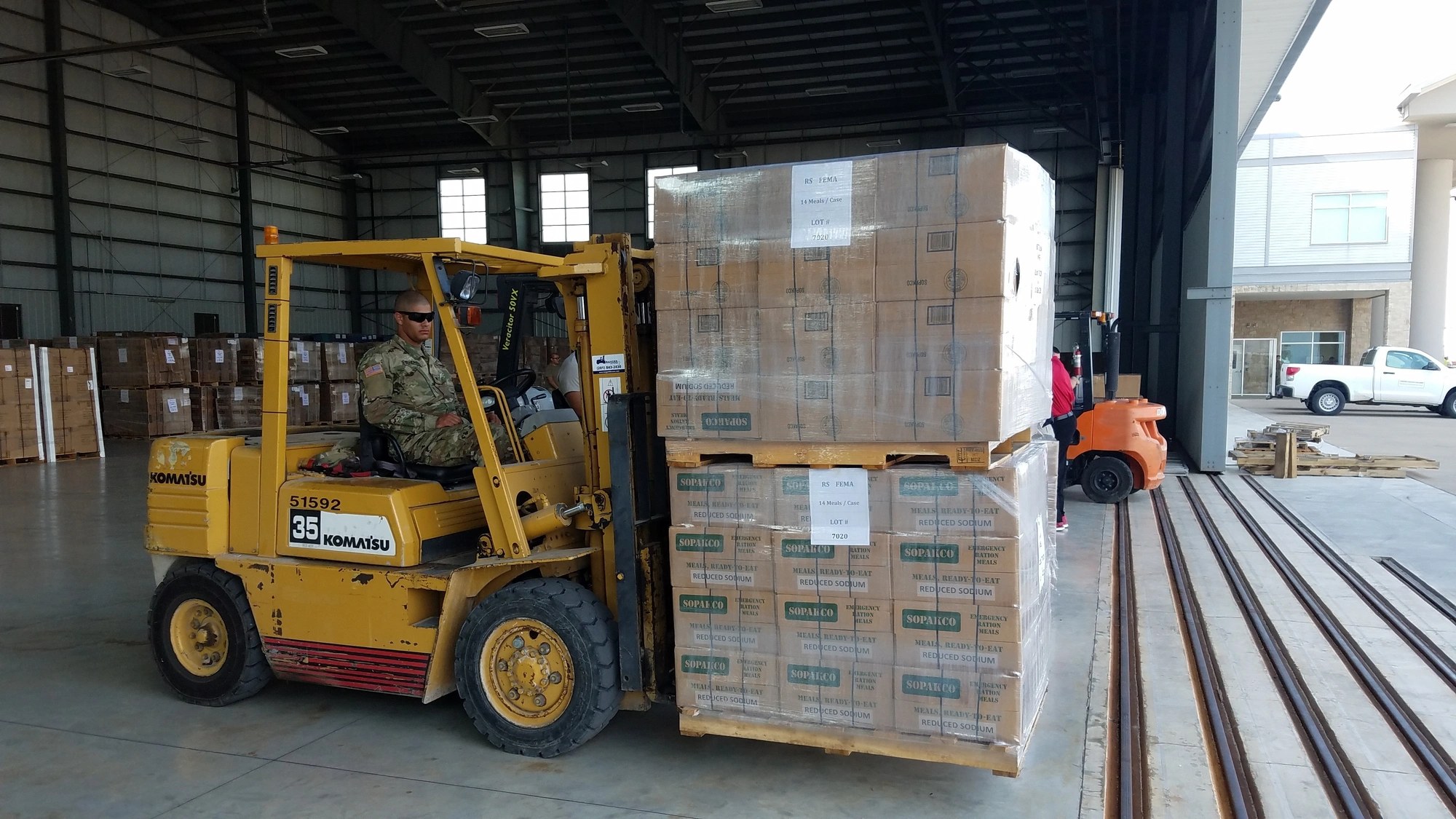 A soldier moves pallets of FEMA emergency meals at a supply warehouse