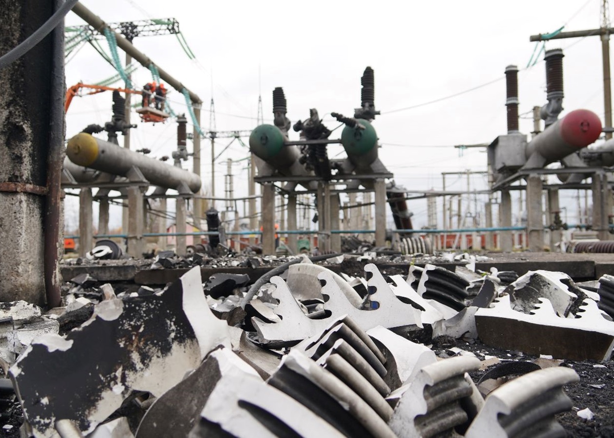 Damaged Ukrainian electricity substation with shattered insulators and a repair crew in a cherry picker, archive photo