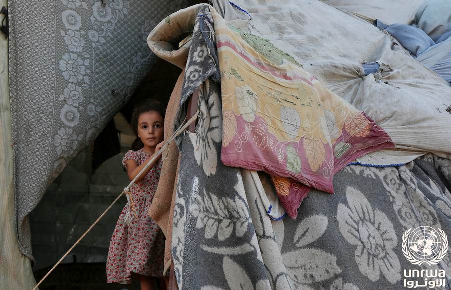 A displaced girl stands at the entrance of a makeshift tent in Deir el-Balah, Gaza, where displaced families shelter during the fragile ceasefire