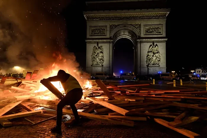 A protester silhouetted against fires on the Champs-Elysees near the Arc de Triomphe during unrest in Paris — file photo for the France bond yields report