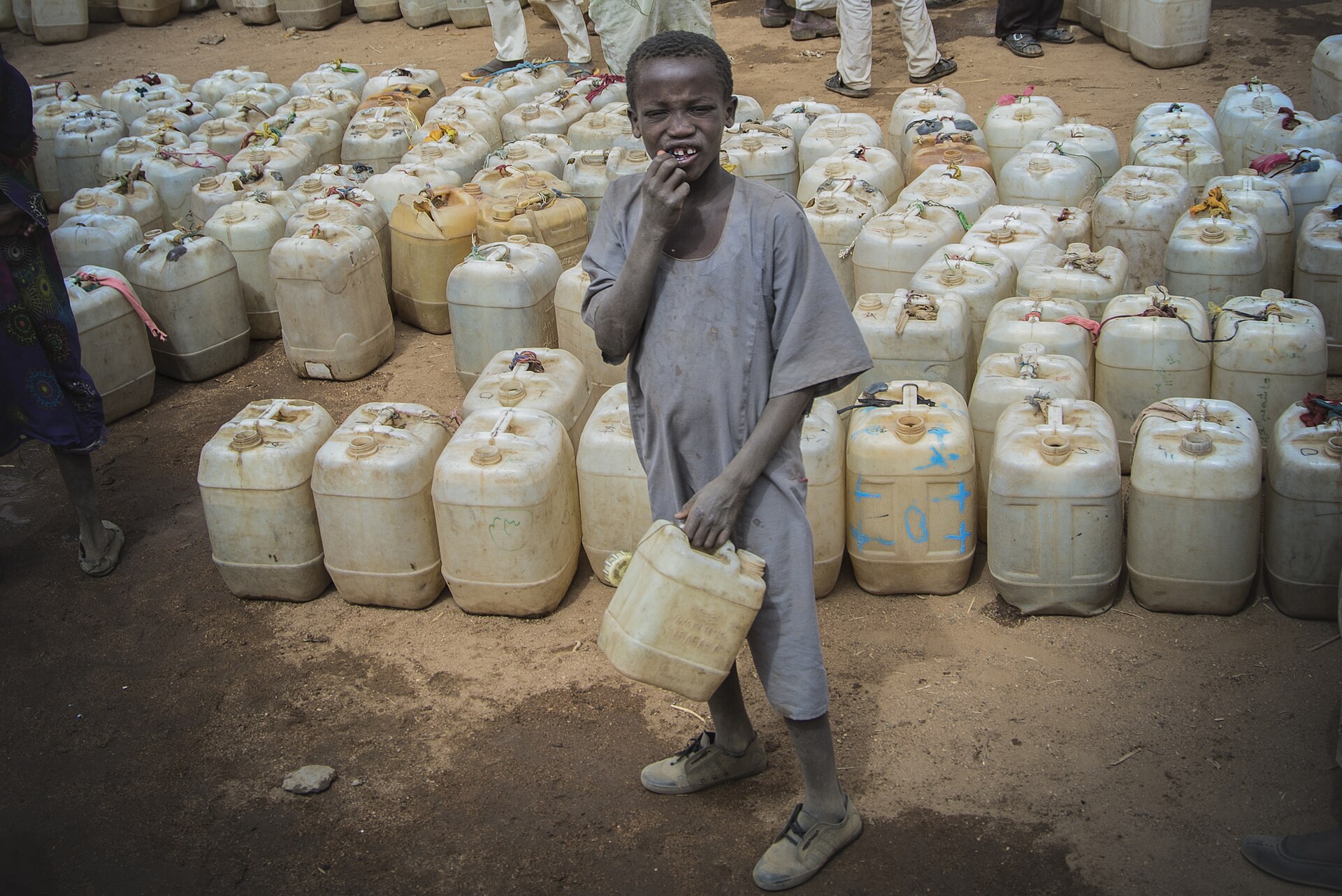 Sudan healthcare attacks — a boy carries a water container past rows of jerrycans at the Sortony displacement camp in North Darfur, where families who fled fighting depend on aid for water, food and basic medical care — file photo