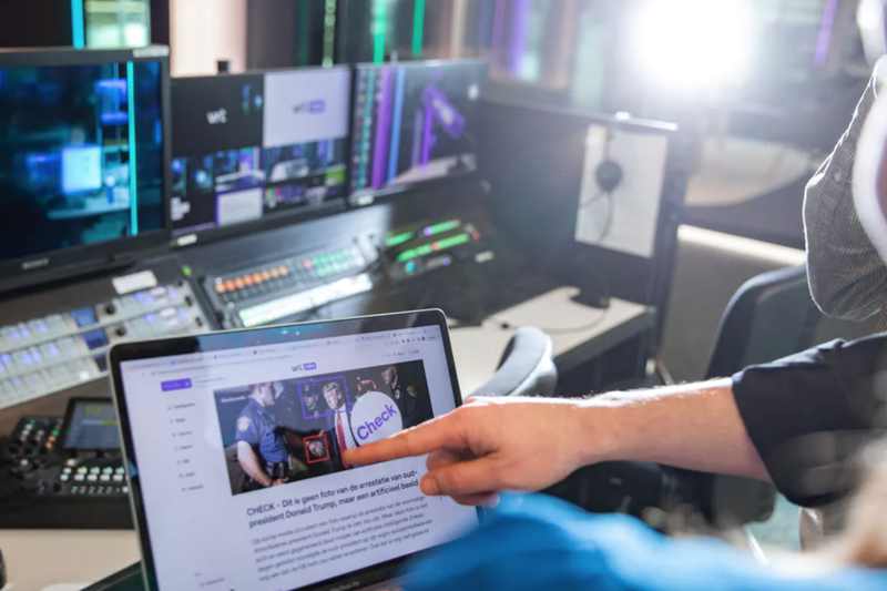 A fact-checker points to a laptop screen while evaluating digital media, illustrating an AI image authenticity check