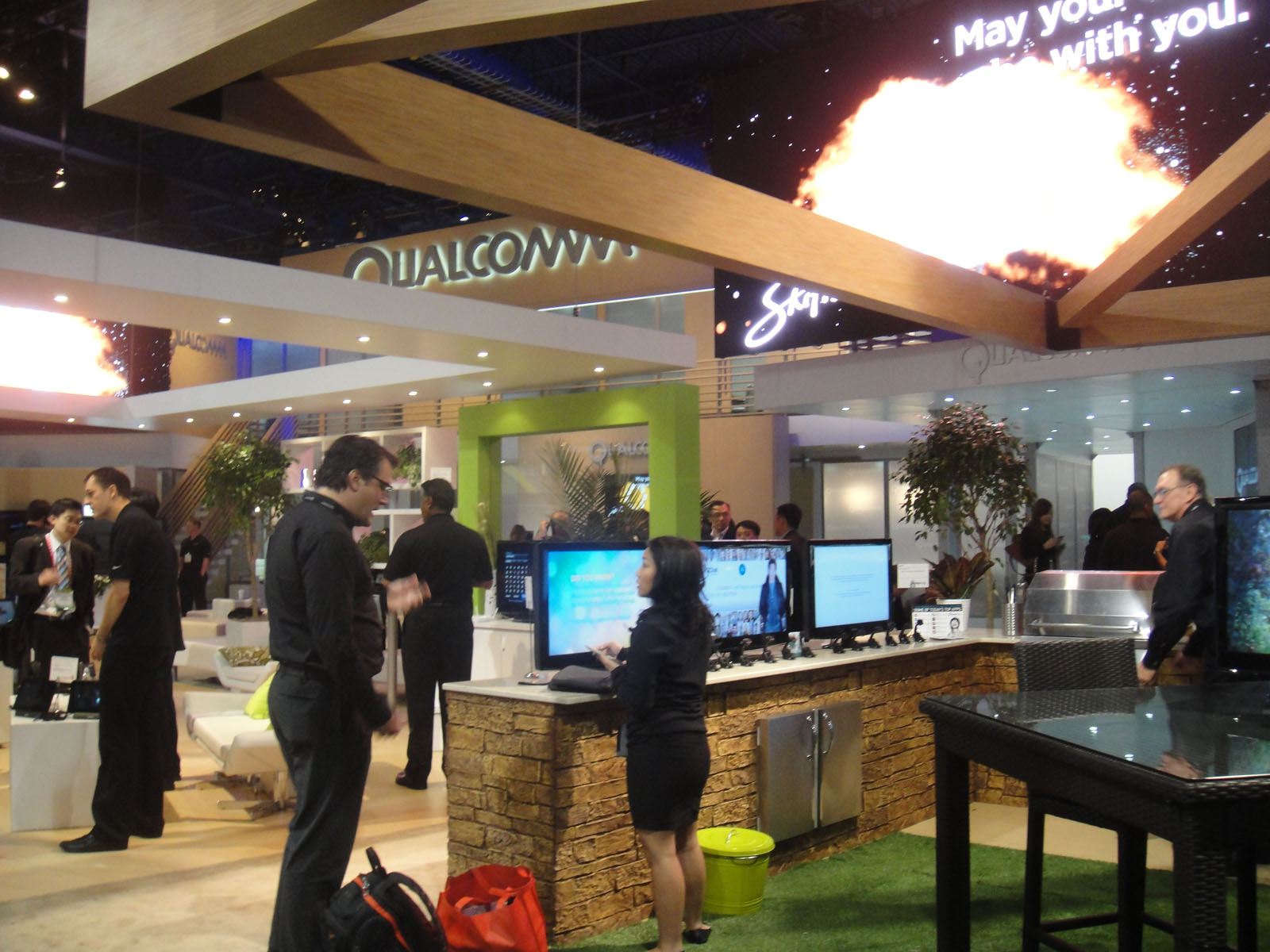 Qualcomm exhibition booth with staff demonstrating products — Qualcomm job cuts will be decided by business priorities and skills