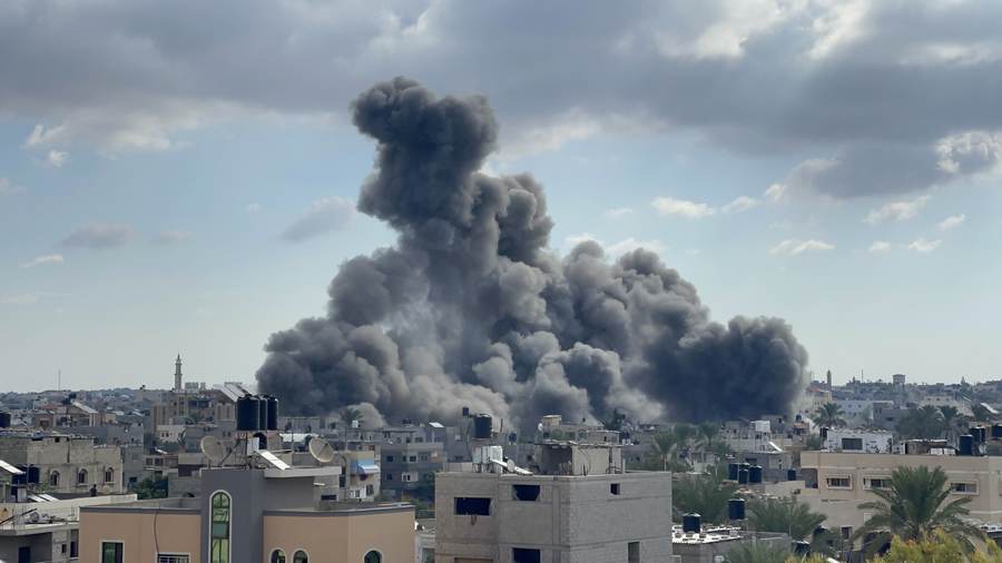 A large plume of smoke rising between civilian buildings in Gaza during morning airstrikes (archival photo, October 2023)