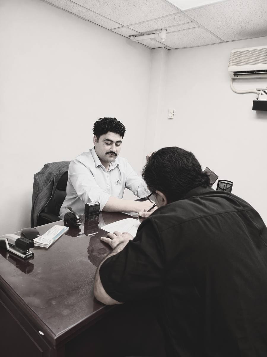 A notary assisting a client with signing documents at a desk, representing real estate closing