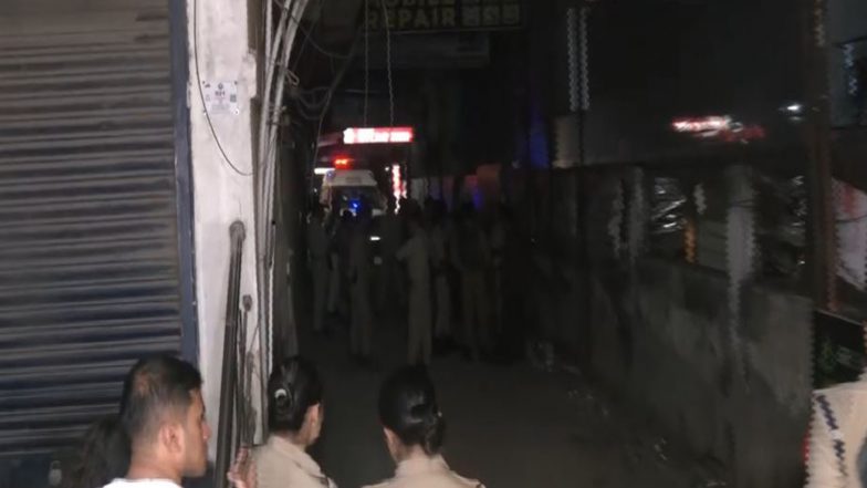 Police officers in a narrow lane beside Hotel Bilas Inn in Guwahati on the night of the Guwahati hotel shooting, with an ambulance in the background