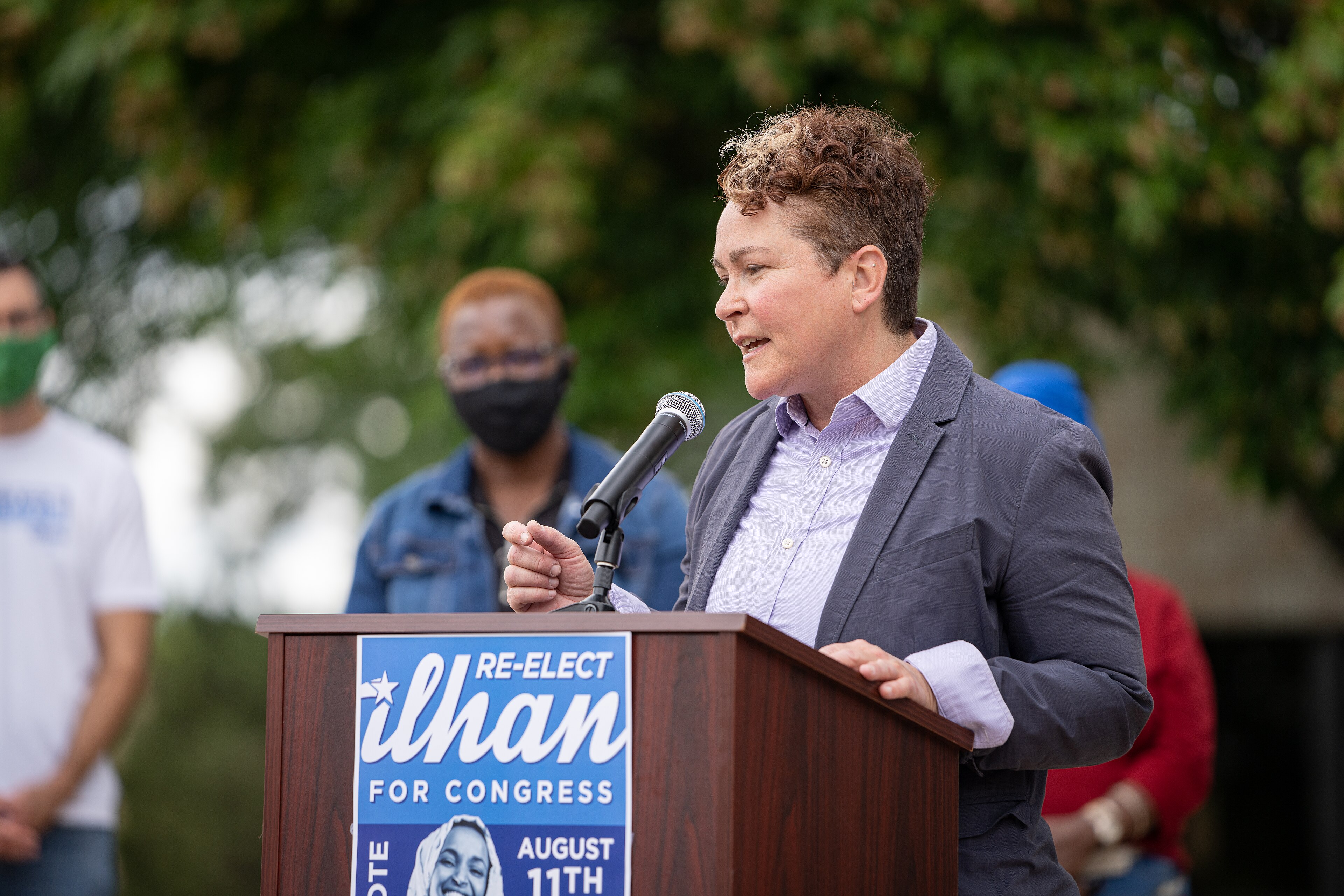 A supporter speaking at a Re-elect Ilhan Omar podium at a Minnesota endorsement press conference in 2020