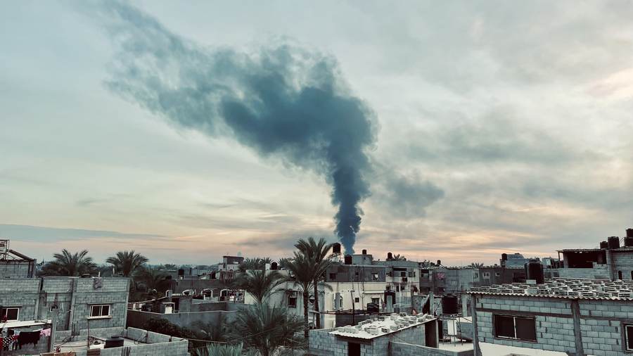 Dark column of smoke rising over Gaza rooftops after an Israeli airstrike (archival photo, December 2023)