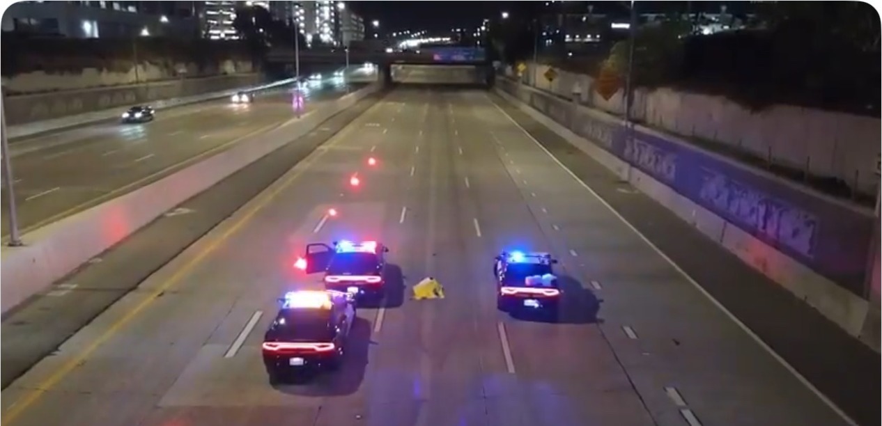 Three CHP patrol cars around a yellow tarp in the eastbound lanes of the 22 Freeway in Santa Ana on Tuesday night — body found on 22 freeway Santa Ana