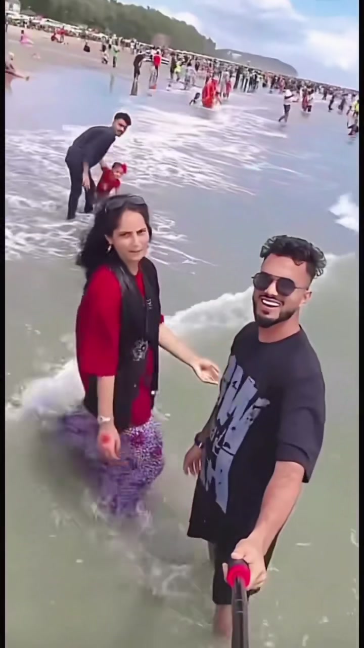 Child swept away by waves — a passerby takes the toddler by the hand in the surf and leads her back as her parents turn toward them