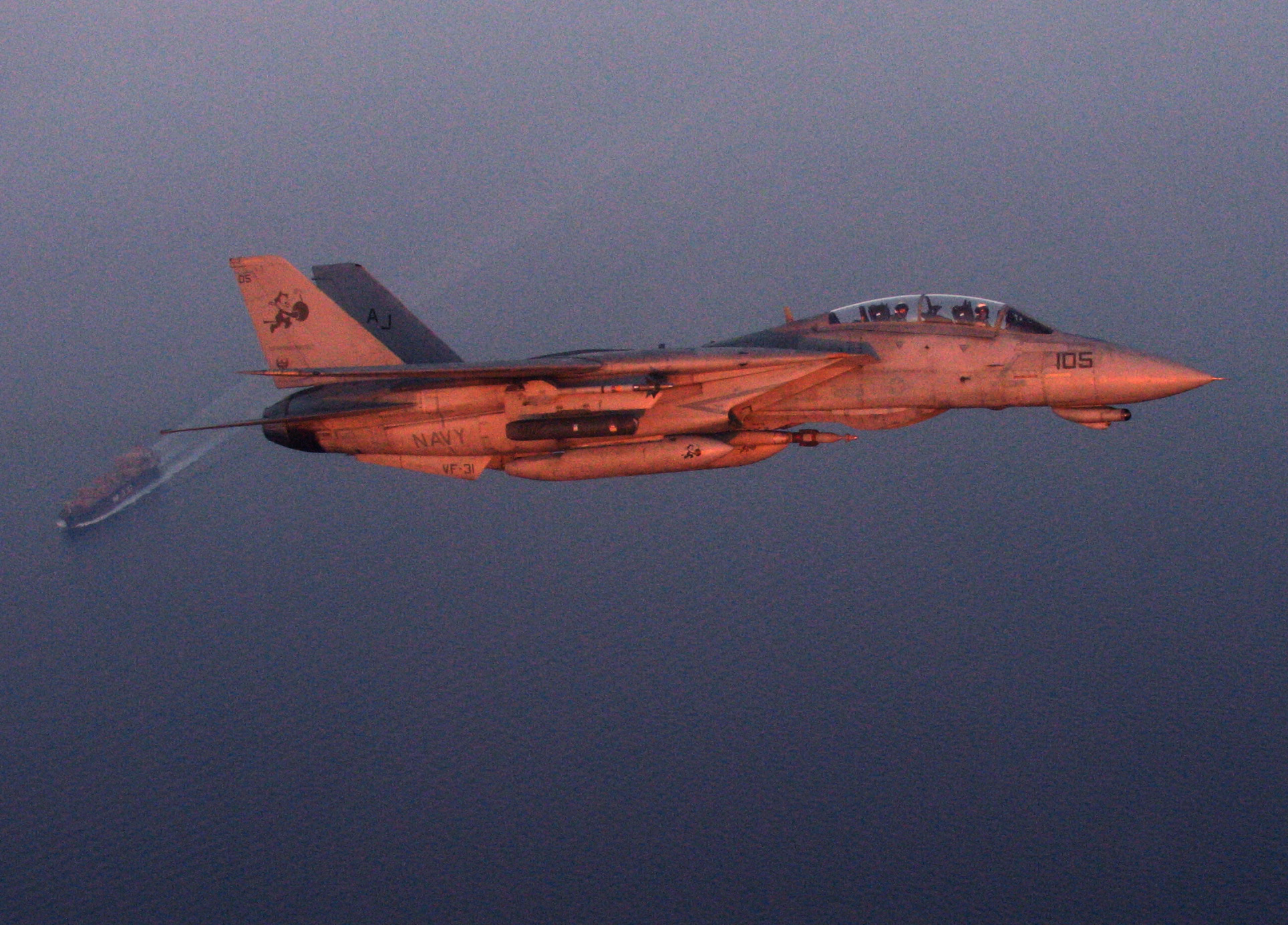 F-14 Tomcat banking over an oil tanker on a maritime security mission over the Persian Gulf at sunset — file photo for the seafarers trapped Strait of Hormuz report
