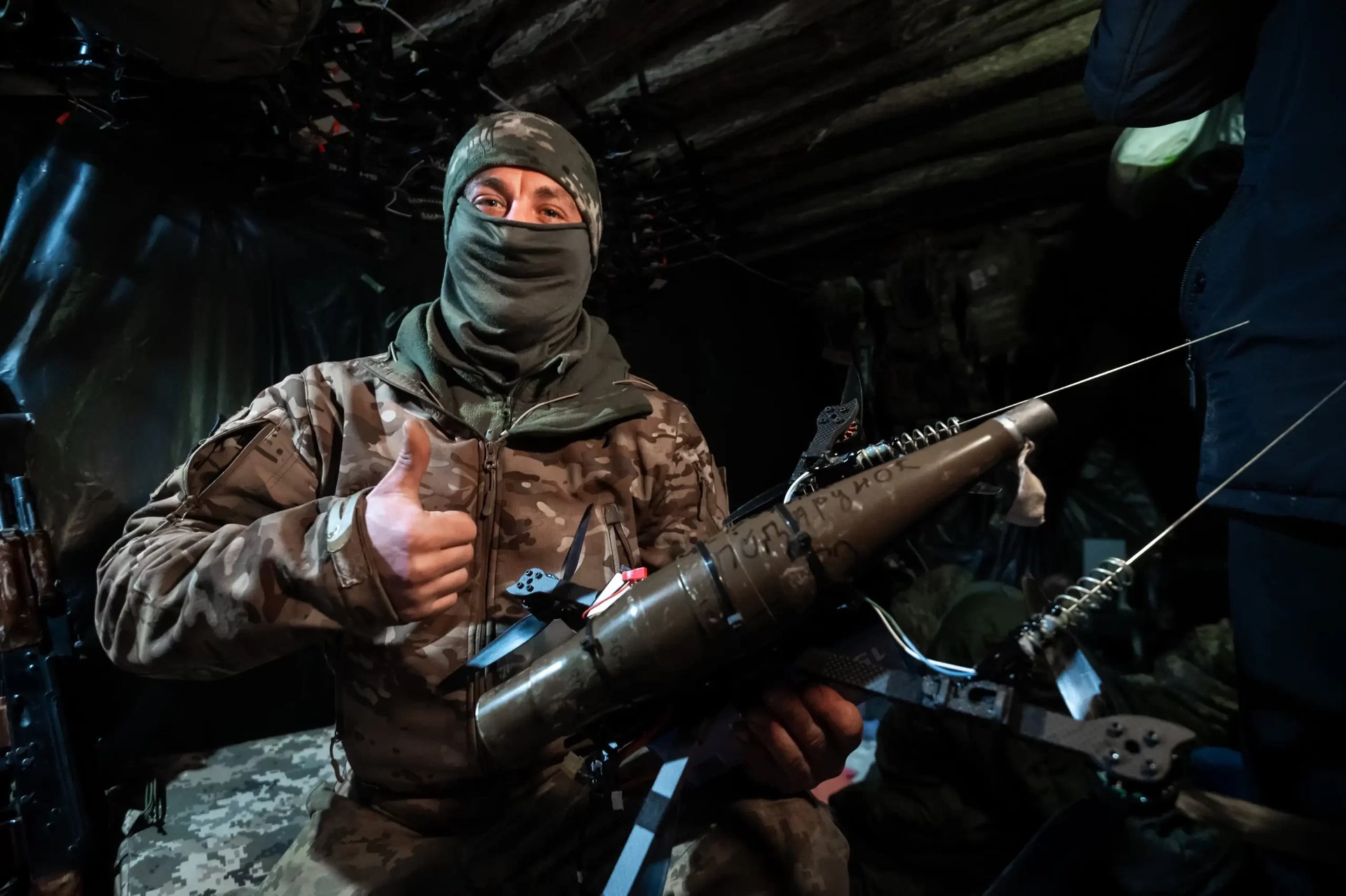 A Ukrainian drone operator holds an FPV attack drone inside a dugout