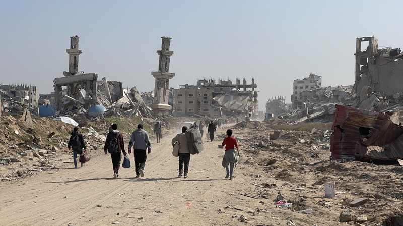 Displaced Gaza residents traveling through a damaged area during the Israel-Hamas war