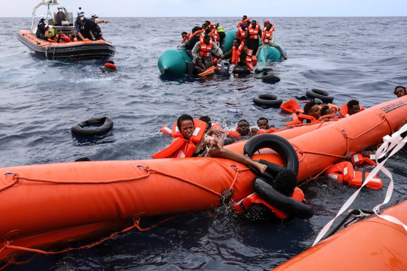 Rescue crews helping migrants from crowded boats in the Mediterranean Sea