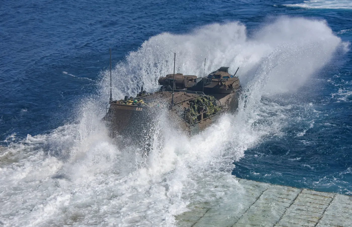 Amphibious vehicles leaving a U.S. naval vessel during a Marine Corps and Navy exercise, illustrating maritime operations involving embarked forces
