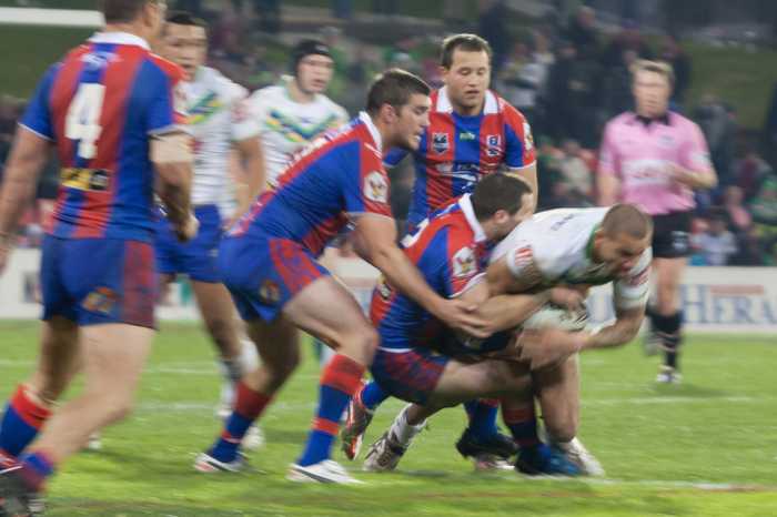 Newcastle Knights players tackle an opponent during an NRL match, file photo — Newcastle Knights farewell car crash