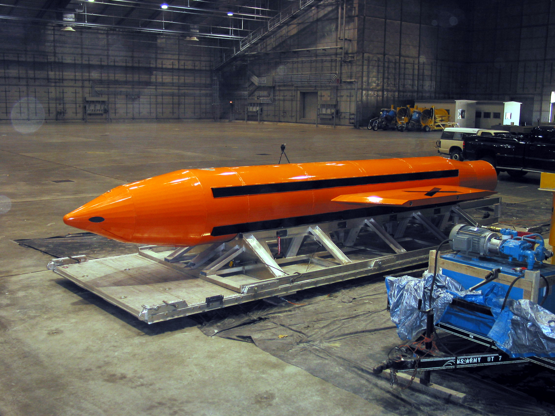 The orange GBU-43/B Massive Ordnance Air Blast Bomb (MOAB) on a cradle in a hangar before its March 2003 test at Eglin Air Force Base, Florida