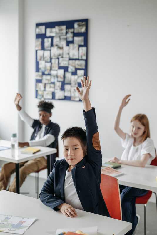 Students raising their hands in a classroom as the NYC schools sexual misconduct probe examines student safeguards