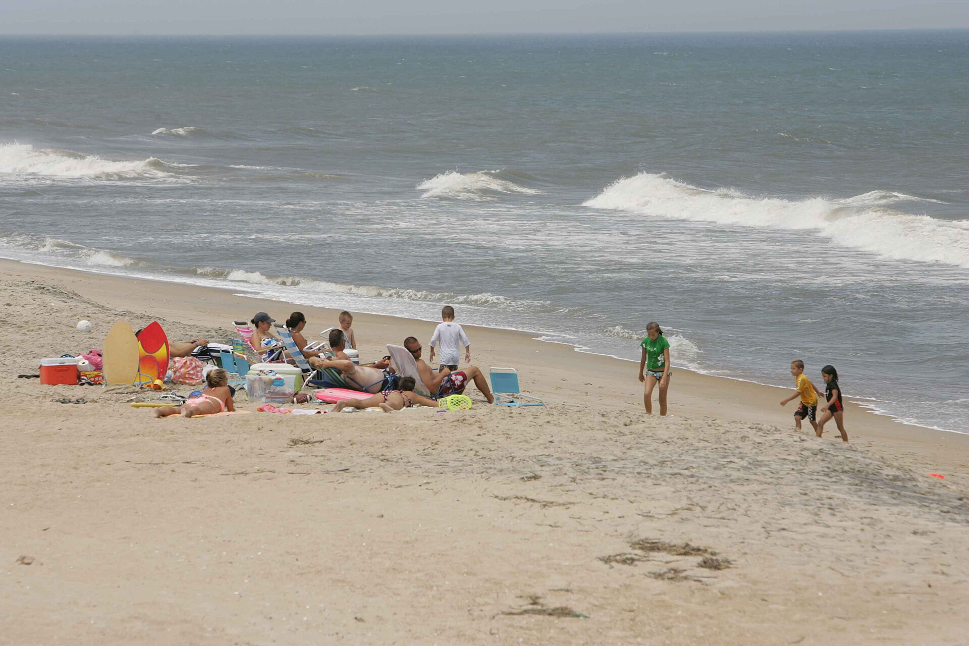 Families at the waterline on a busy beach — the viral clip has renewed argument about phones, filming and supervision in the shallows