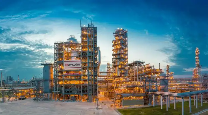 An illuminated Lukoil oil refinery complex, representing the refineries included in the international assets sale