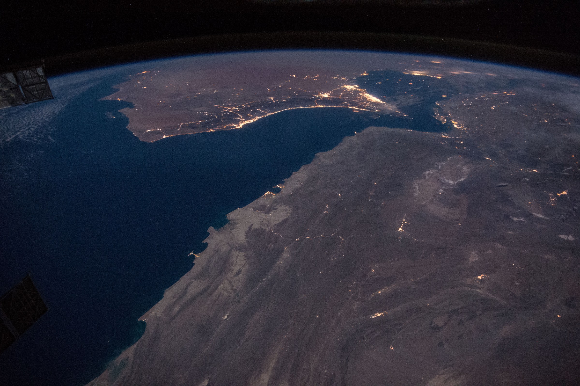The Strait of Hormuz and the Gulf of Oman at night, photographed from the International Space Station — the IRGC seven vessels hit claim covers the northern Persian Gulf and the waters west of the strait, where Tehran says three vessels struck mines