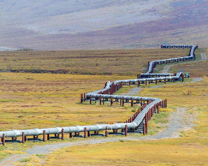 An oil pipeline crossing open land, representing energy infrastructure changing hands