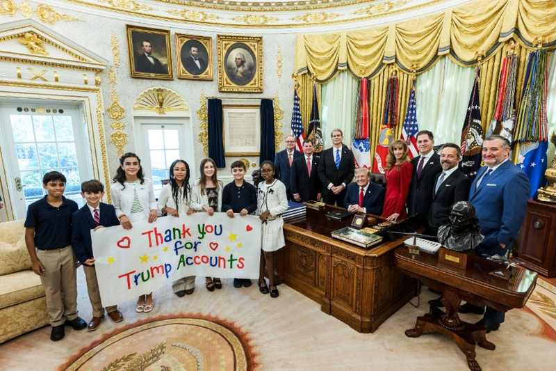 President Trump in the Oval Office on October 7, 2026, with Michael and Susan Dell, Treasury and IRS officials, and children holding a Thank You for Trump Accounts banner.