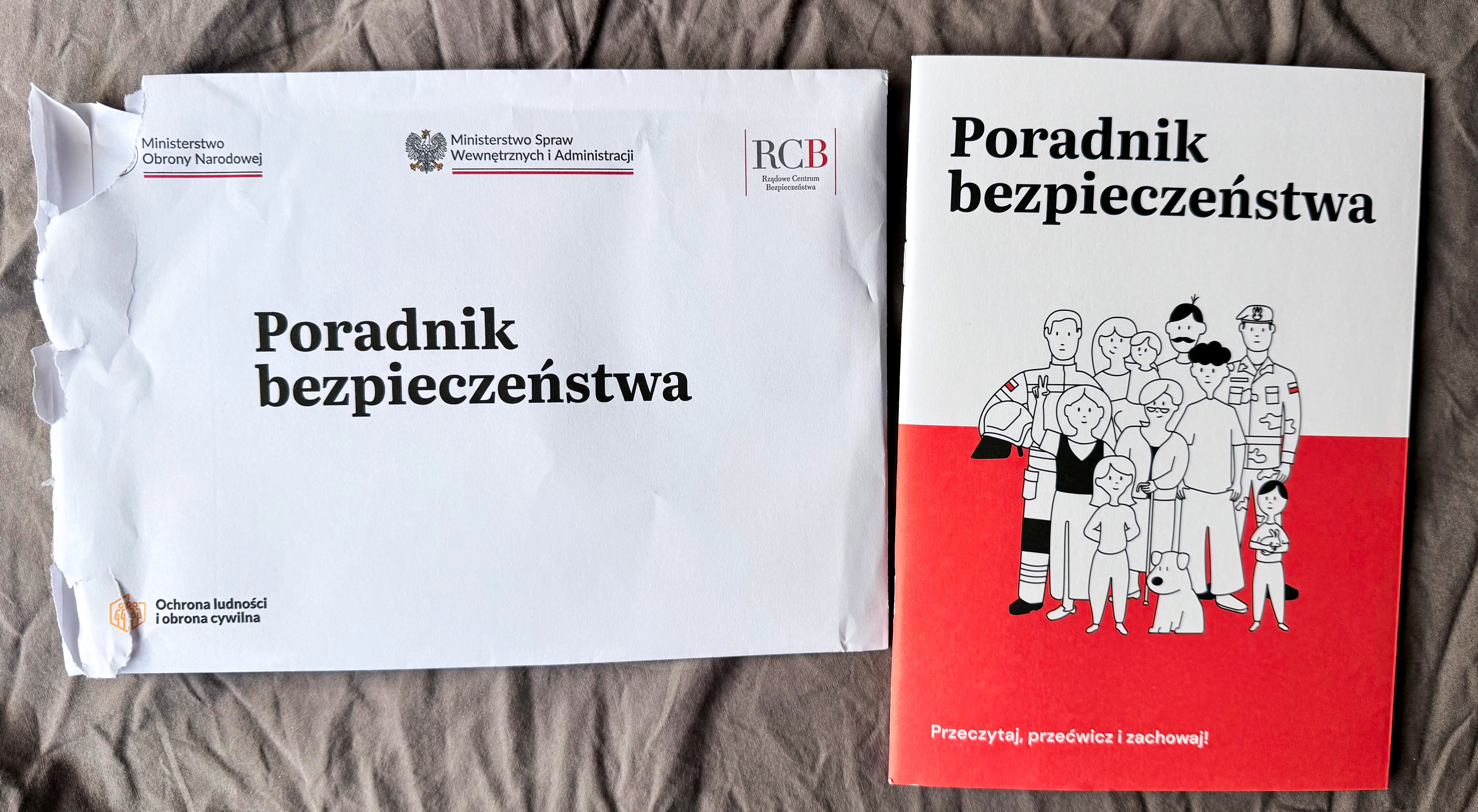 Poland's Poradnik bezpieczeństwa (Safety Guide) and its government delivery envelope, mailed to nearly 17 million households as Europe prepares citizens for war