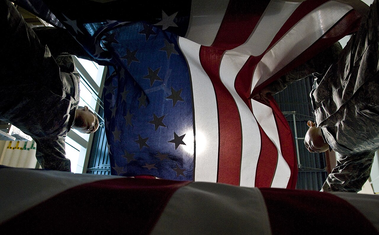 U.S. Air Force personnel practice placing a flag over a casket, illustrating the Dover dignified transfer for the six Port Shuaiba fallen