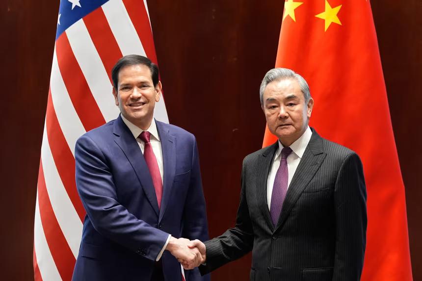 U.S. Secretary of State Marco Rubio and Chinese Foreign Minister Wang Yi shaking hands between national flags