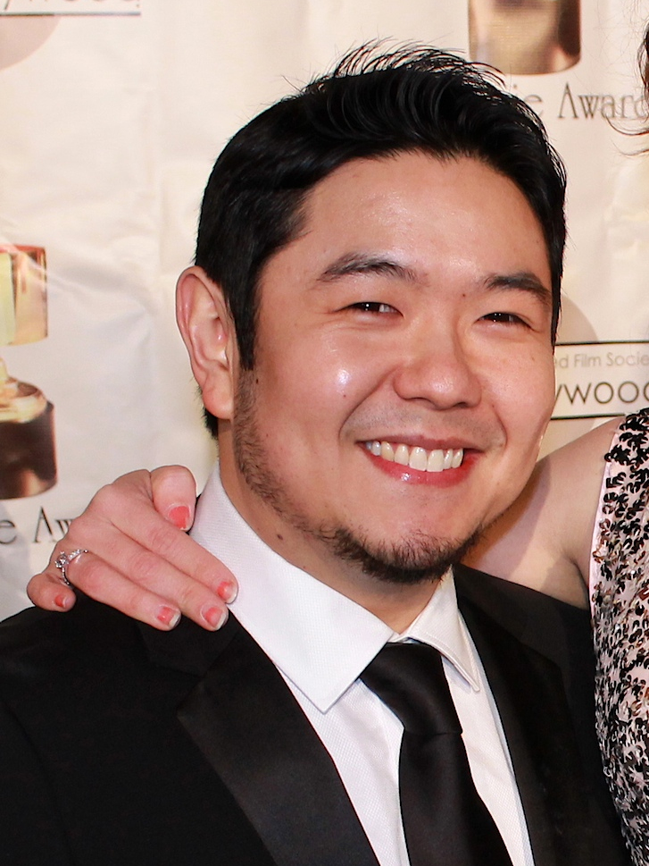 A smiling Eric Bauza in a suit at the 41st Annie Awards in 2014