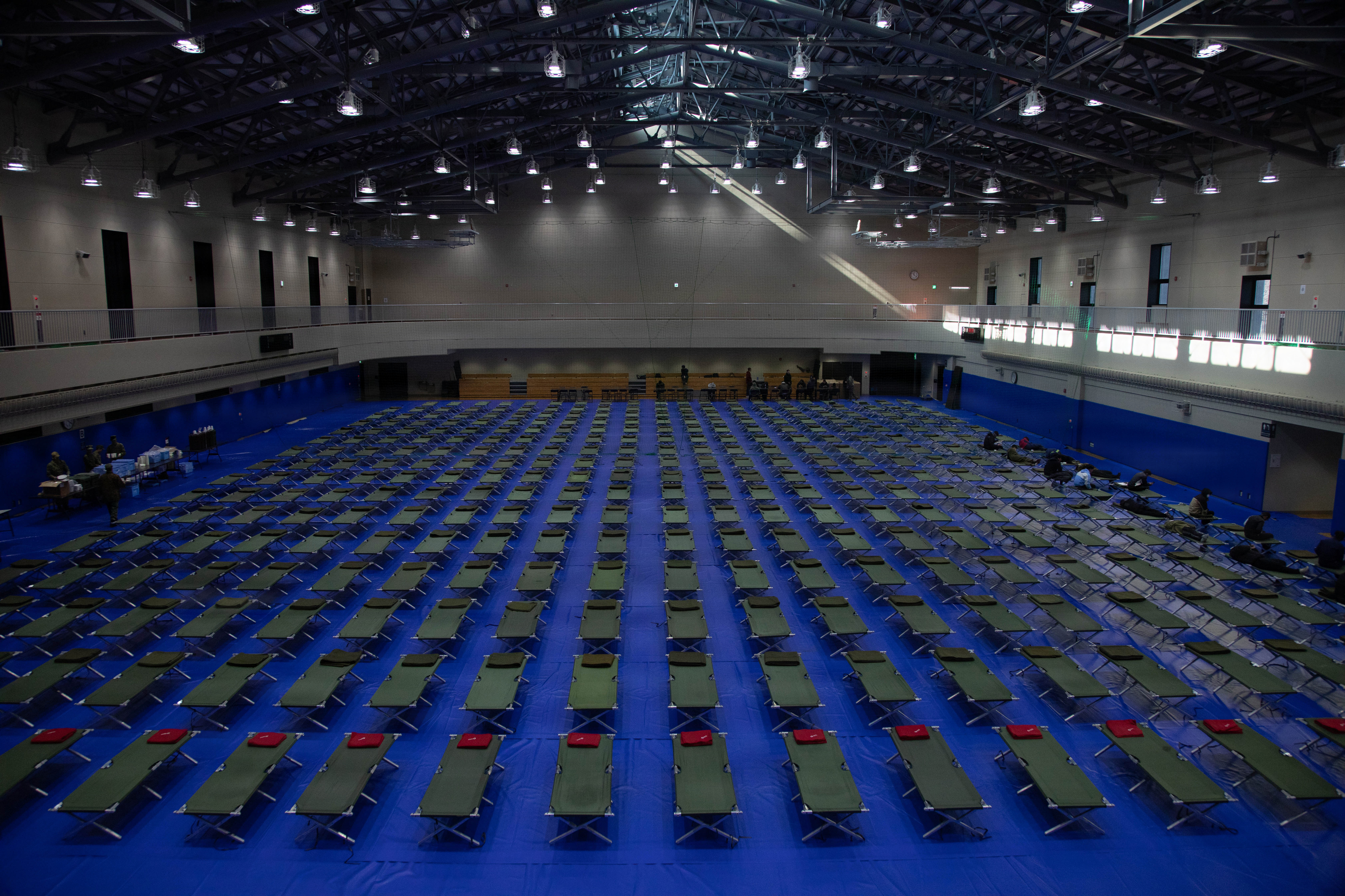 Rows of cots laid out in a gymnasium prepared for simulated evacuees during the Nankai Rescue 2026 exercise in Iwakuni, Japan