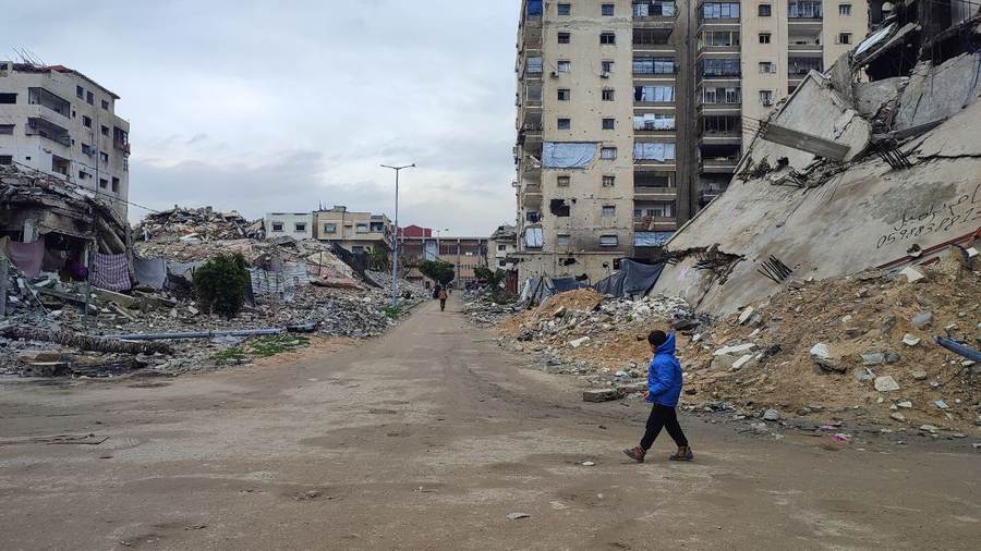 A child walks past damaged apartment buildings on Al-Wahda Street in Gaza City