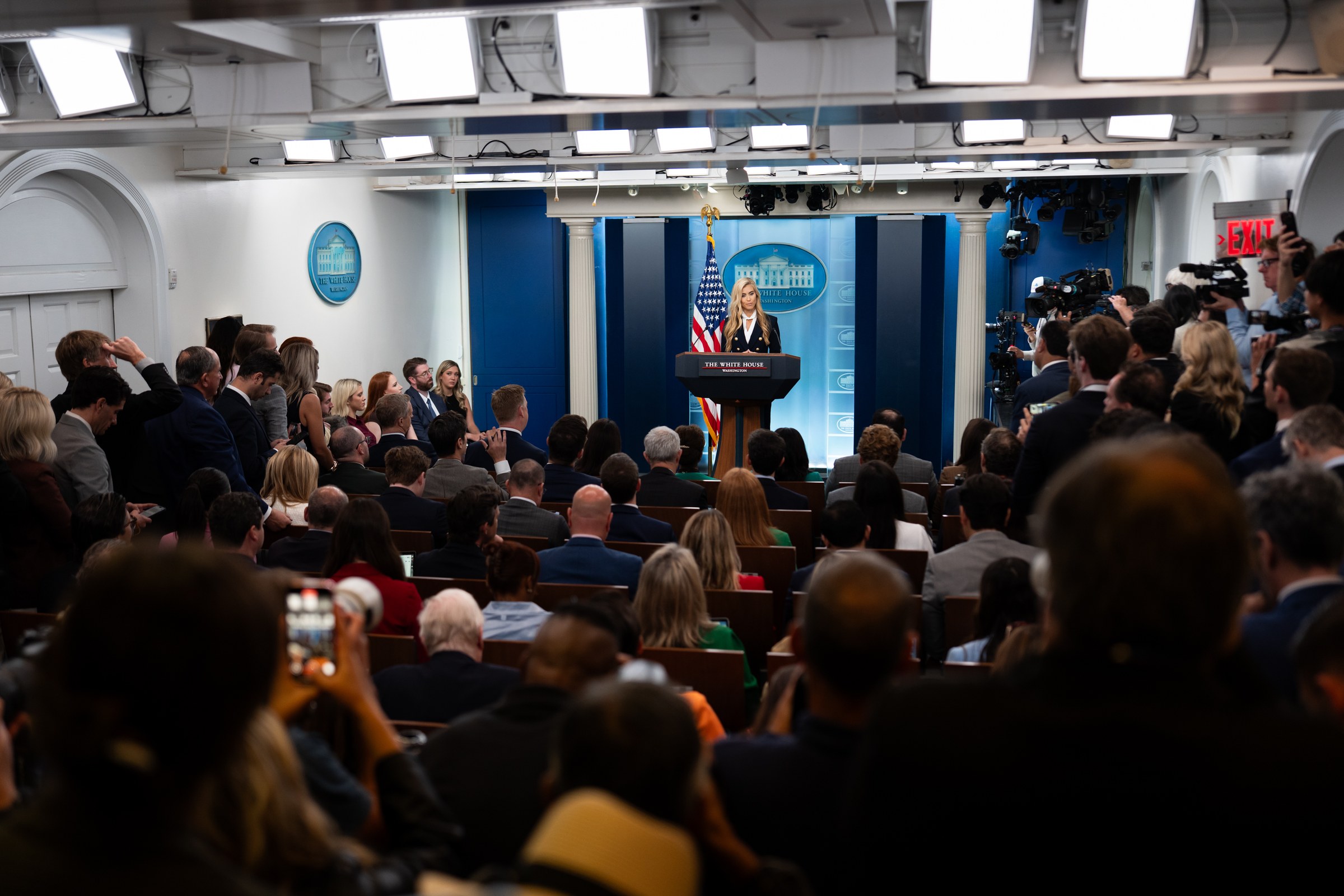 The White House press corps watching Katie Zacharia at the podium during her first briefing on October 13, 2026
