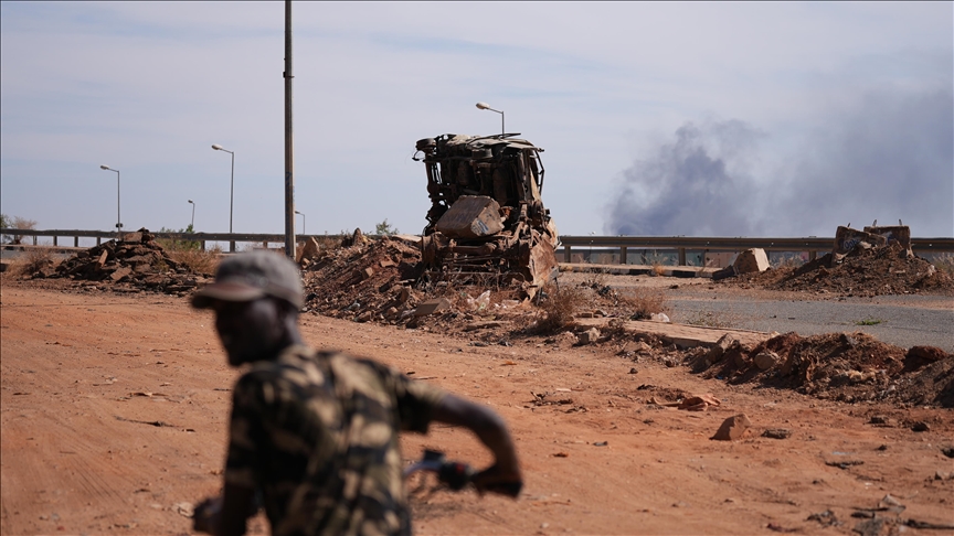 A damaged military vehicle and smoke in a contextual image published with El Fasher battle reporting