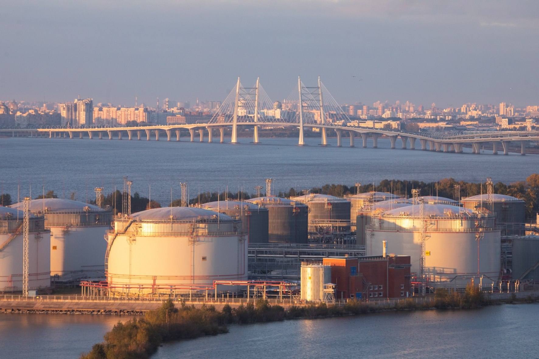 Storage tanks at the Petersburg Oil Terminal with the Western High-Speed Diameter bridge and the St. Petersburg skyline behind — the terminal at the centre of the St Petersburg oil terminal fire