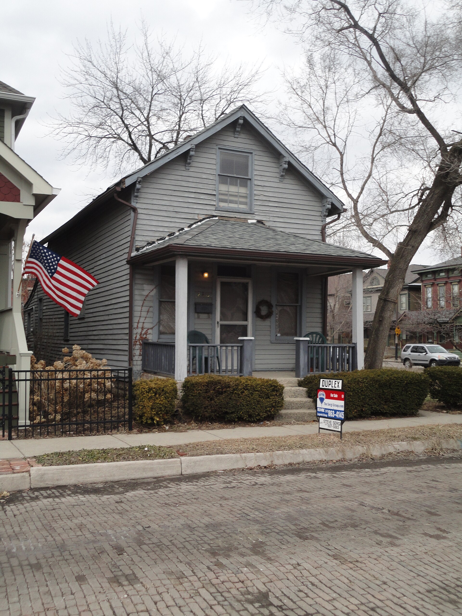 A for-sale sign in front of a house on a brick street in Indianapolis — pending home sales September 2026 file photo