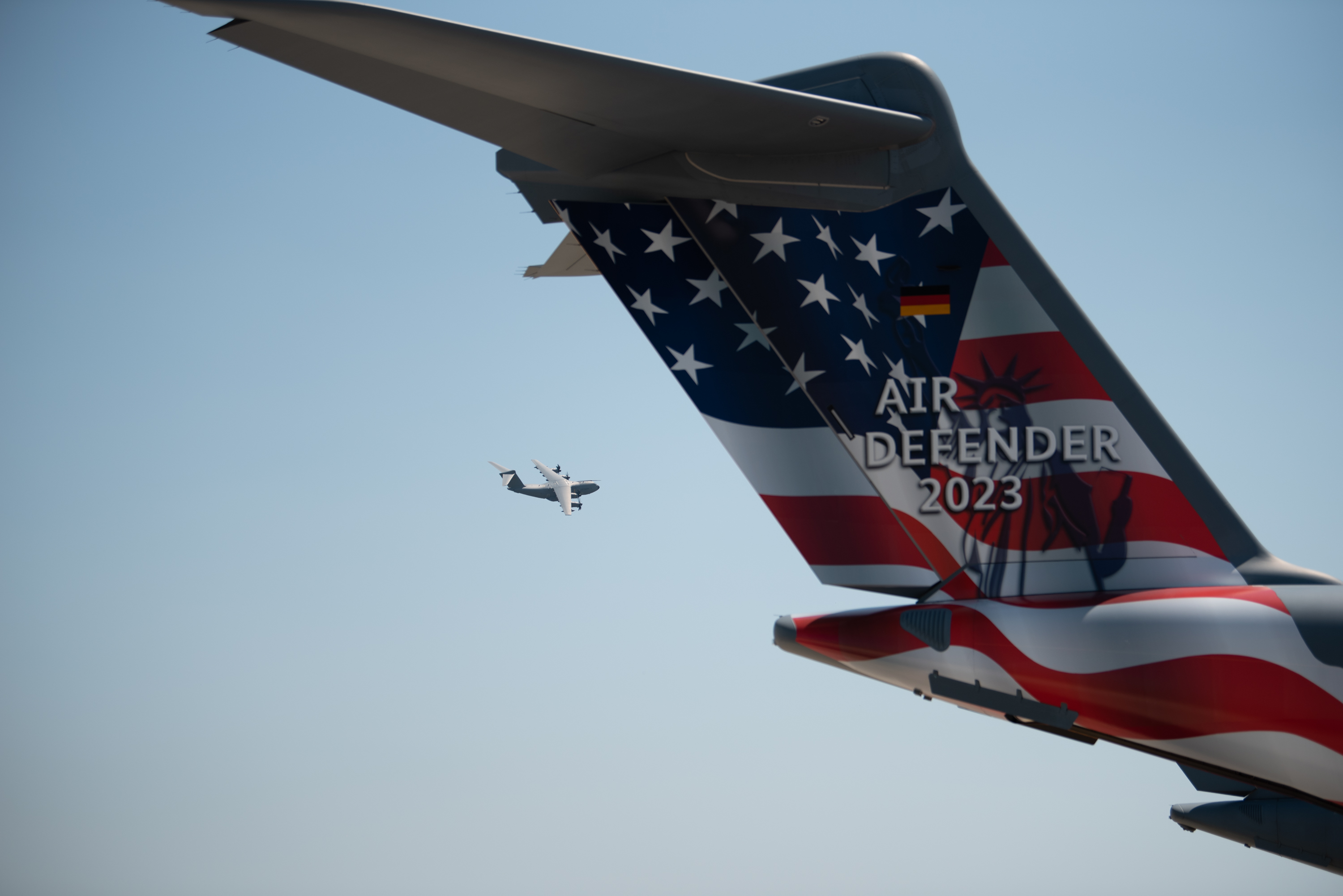 Germany Russian sabotage threat — a German A400M Atlas in flight at Wunstorf Air Base during Exercise Air Defender 2023, past a transport aircraft tail in Air Defender livery